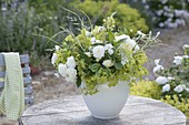 Green and white bouquet on garden table alchemilla, pink