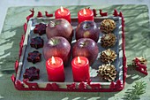 Wooden coaster with 4 red candles, apples (malus), cones