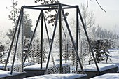 Raised beds with trellises in a snow-covered garden