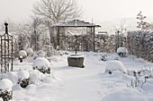 Snow-covered rose beds, Buxus in ball shape, hedge, gazebo