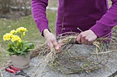 Easter table decoration with wreath of twigs, grasses and yellow primrose