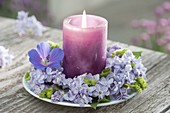 Candle in wreath from Syringa with a blossom of geranium