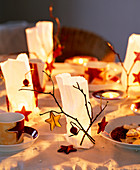 Pergamenttüten mit Teelicht, Zweigen und Sternen dekoriert als Tischdeko