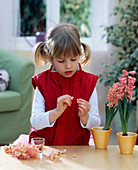 Mädchen fädelt Hyacinthenblüten auf eine Perlenschnur