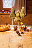 Tiny crocheted Christmas trees and tealight holders on wooden table