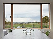 View of landscape through large window across dining table