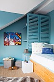 Petrol-blue walls and shelves behind slatted screen in boy's bedroom