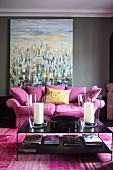 Scatter cushions on pink couch and black coffee table in front of modern painting