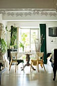 Table with pedestal leg and house plants in dining room with white floor