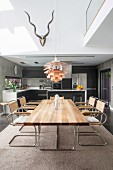 Modern dining table and cantilever chairs in front of open-plan kitchen