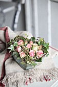 Romantic arrangement of ivy and roses in heart-shaped vintage container