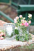 Romantic arrangement of roses and lit candles in glass vases