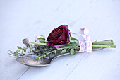 Posy with deep red ranunculus tied to vintage cutlery