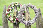 Two flower wreaths hung from rustic garden fence