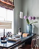 Table lamp, vase of flowers and books on masculine desk