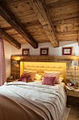 Double bed with yellow button-tufted headboard surrounded by rustic wooden panelling