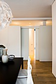 View past dining table to wall with sliding doors, transom window and fitted cupboards