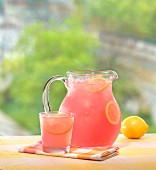 Eisgekühlte pinkfarbene Sommerlimonade in Krug und Glas