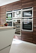 Dark wooden cupboards with integrated appliances in modern kitchen