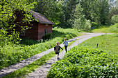 Children running along country lane through summer meadows