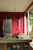 Island counter with concrete worksurface in front of red wall