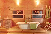 White, free-standing bathtub and elephant ornament in wood-panelled bathroom