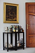 Drinks table below gilt-framed painting on wall
