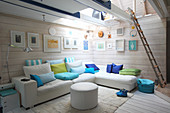 White leather couch combination with colourful scatter cushions in living room with wooden walls and skylight