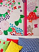 Various scatter cushions in front of colourful wall decorated with large floral motifs