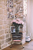 Vase of roses on old trolley against exposed stone wall