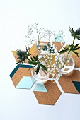 Vases of thistles and gypsophila on hand-made, hexagonal, painted cork coasters