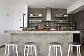 Cast concrete kitchen counter and silver bar stools in open-plan kitchen
