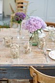 Table set with biscuits in glasses and vases of hydrangeas