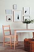 Collection of pictures above chair and vase of flowers on table