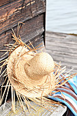 Hand-made straw hat leaning against wooden wall