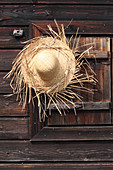 Hand-made straw hat hung on wooden wall