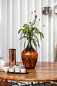 Brown glass vase and coffee set on wooden table outside house