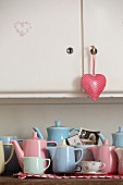 Collection of retro pastel jugs on kitchen dresser with heart-shaped pendant on cupboard door