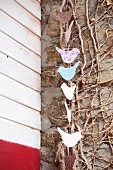 Garland of birds on rustic wall with leafless winter climbing plant