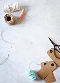 Reels of yarn and twine, cardboard labels and scissors on marble table