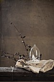 Small china bird under glass cover and branches on white tablecloth