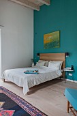 Simple bed in bedroom with high ceiling and blue wall