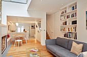 Offener Wohnraum mit grauem Sofa und Bücherregal