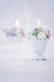 Romantic flower arrangement and lit candle in front of mirror