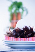 White egg, napkin and feather on stacked plates