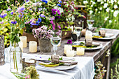 Set table decorated with wildflowers and candles in garden