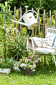 Seating area in front of paling fence decorated with watering can and bouquets of wildflowers