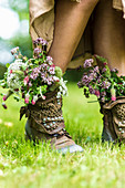Girl with bunches of wildflowers stuffed in studded leather boots