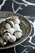 Hens' eggs decorated in black and white in antique silver dish