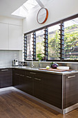 Modern kitchen with dark wooden fronts and louvre windows